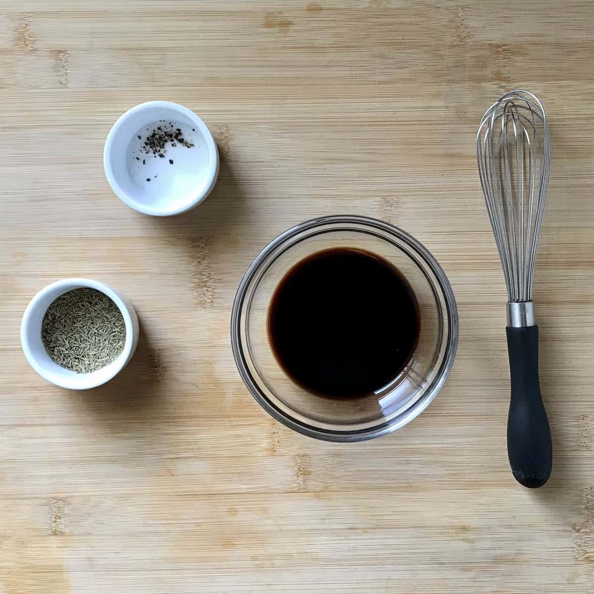 Ingredients for balsamic vinaigrette on a wooden board.