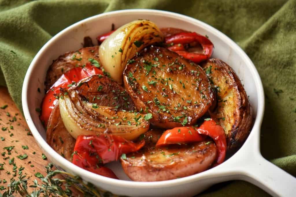Roasted Red Potatoes, caramelized onions and roasted bell red peppers in a white dish.