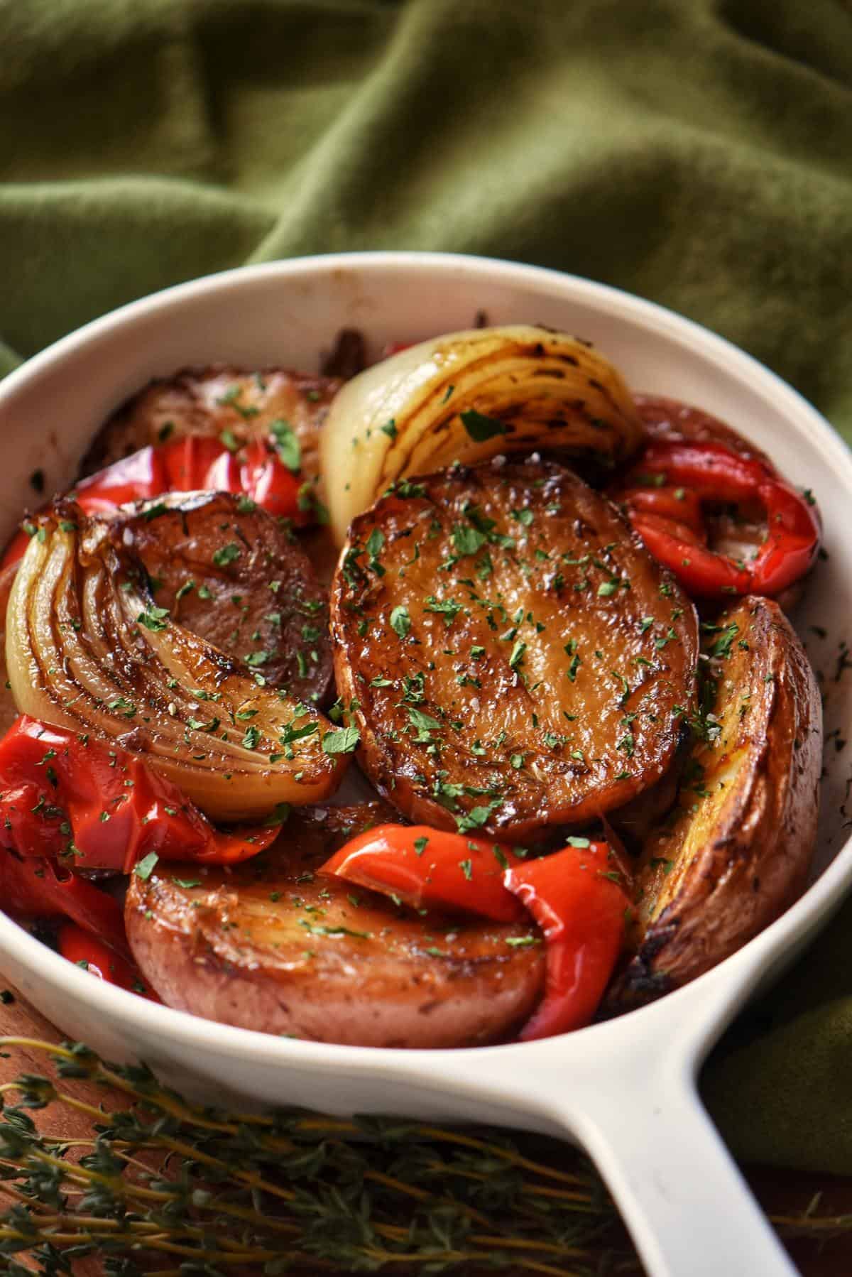 Roasted Red Potatoes, caramelized onions and roasted bell red peppers in a white dish.