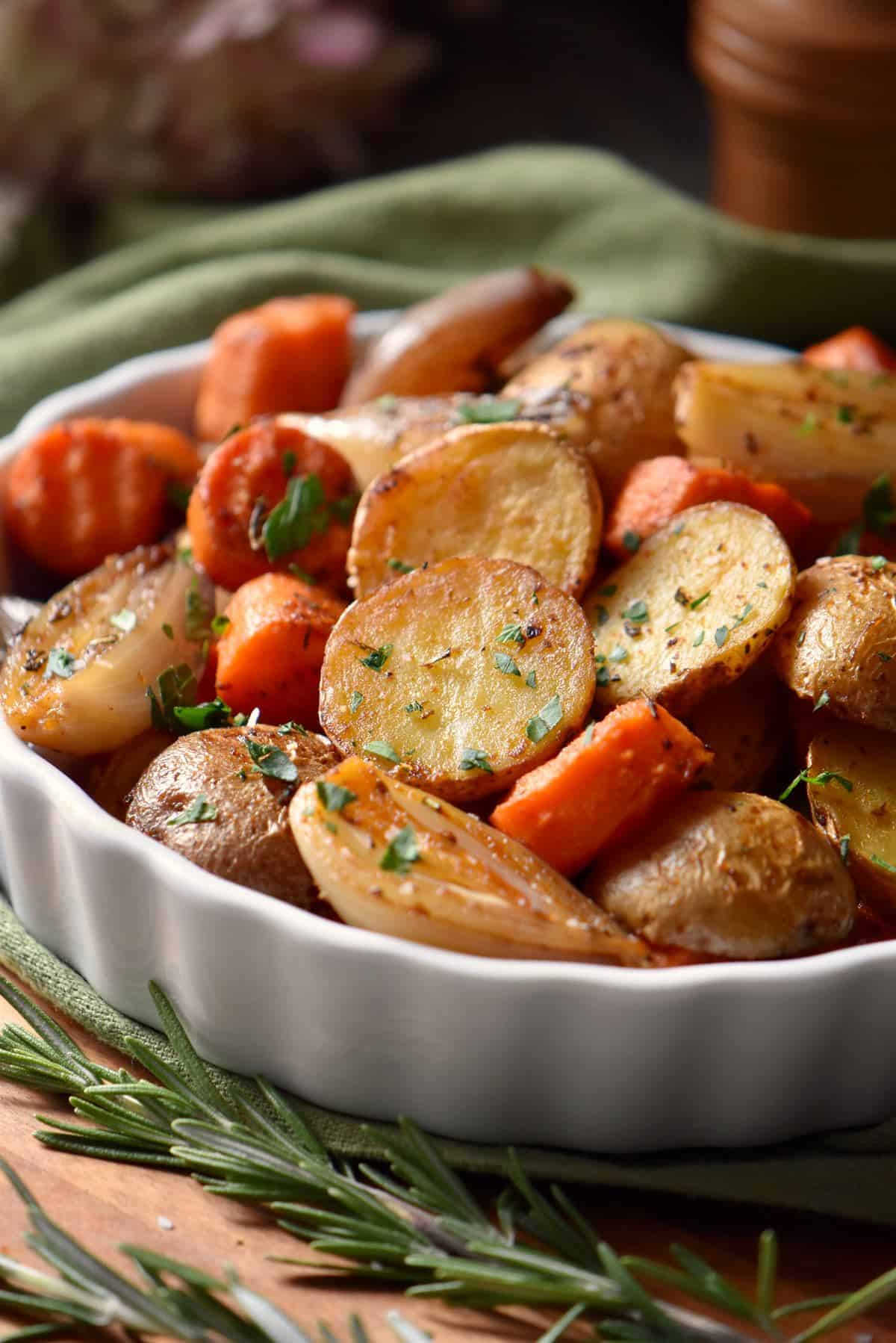 Oven roasted small potatoes and carrots in a white dish.