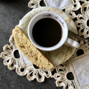 An overhead view of a cup of espresso with an almond biscotti.