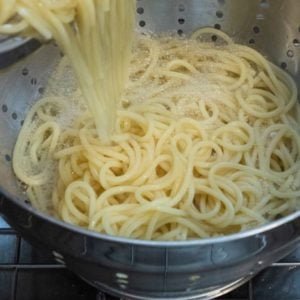 Spaghetti being drained in a colander.