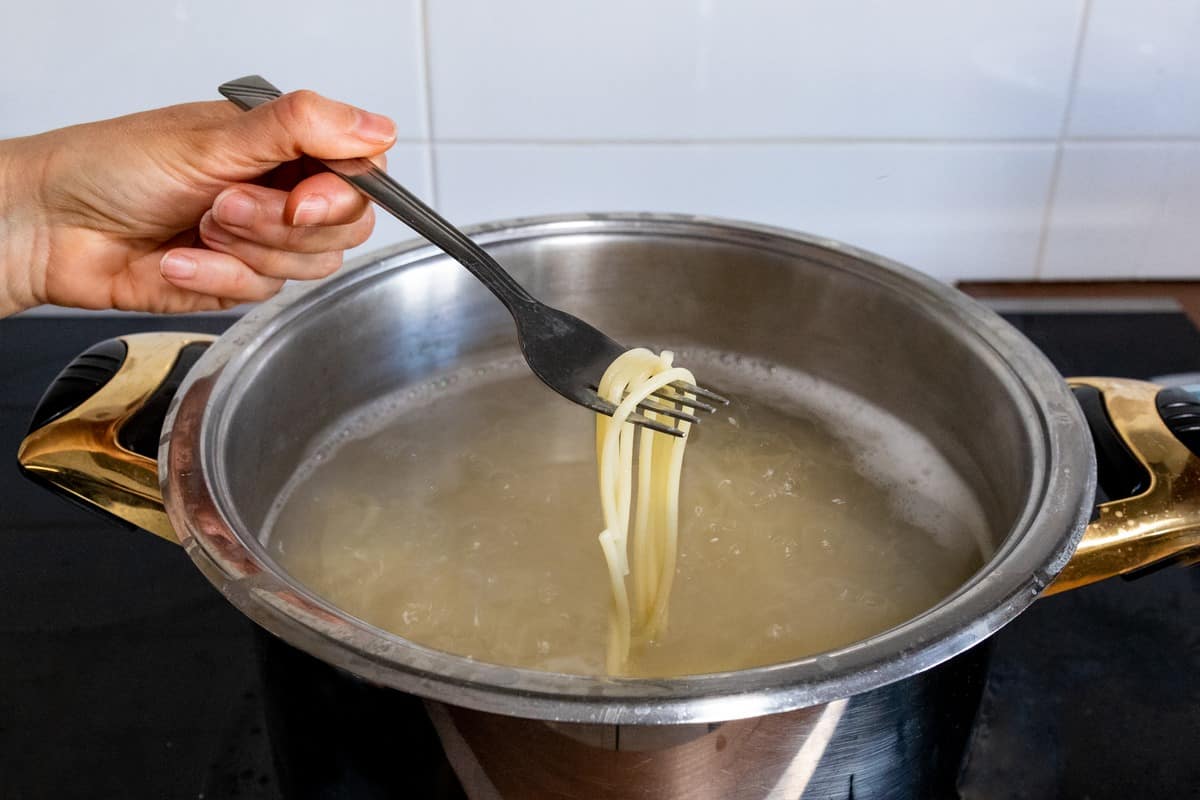 Spaghetti being removed from a pot of pasta.