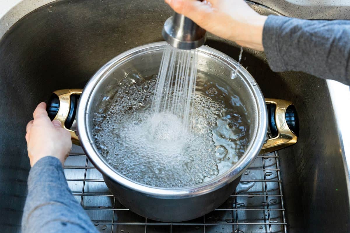 A large pot being filled with water. 