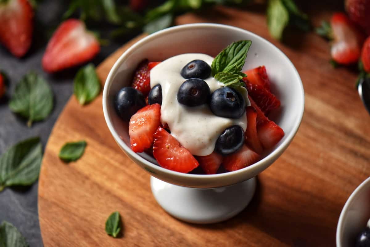 A serving of fruit topped with sweet ricotta. 