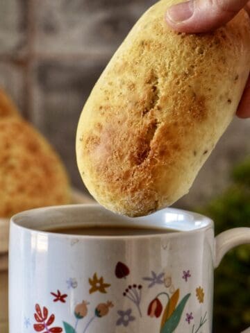An Italian breakfast cookie about to be dunked in a cup of coffee.