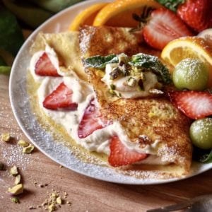 Ricotta filled crepes on a white plate.