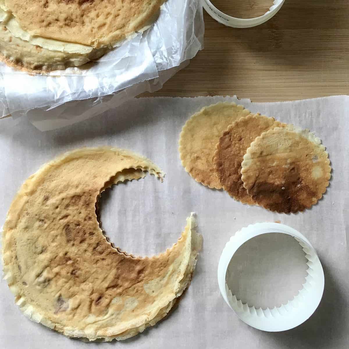 A cookie cutter and crepes on parchment paper.