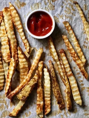 Crinkle cut fries on parchment paper.