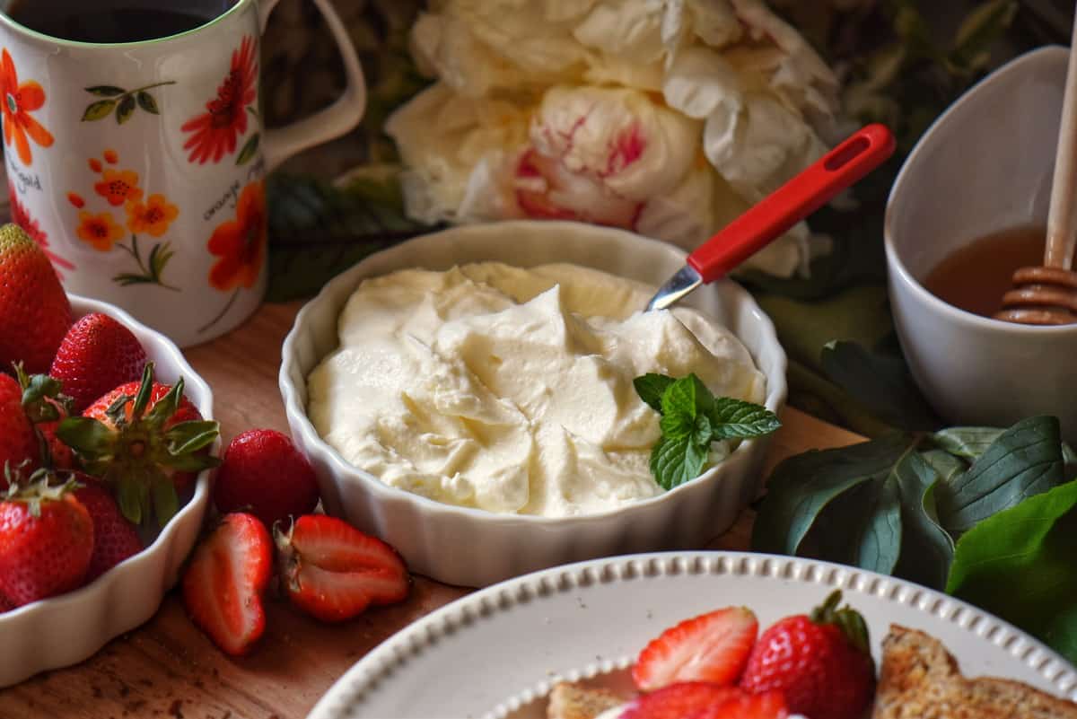 A bowl of ricotta surrounded by strawberries.