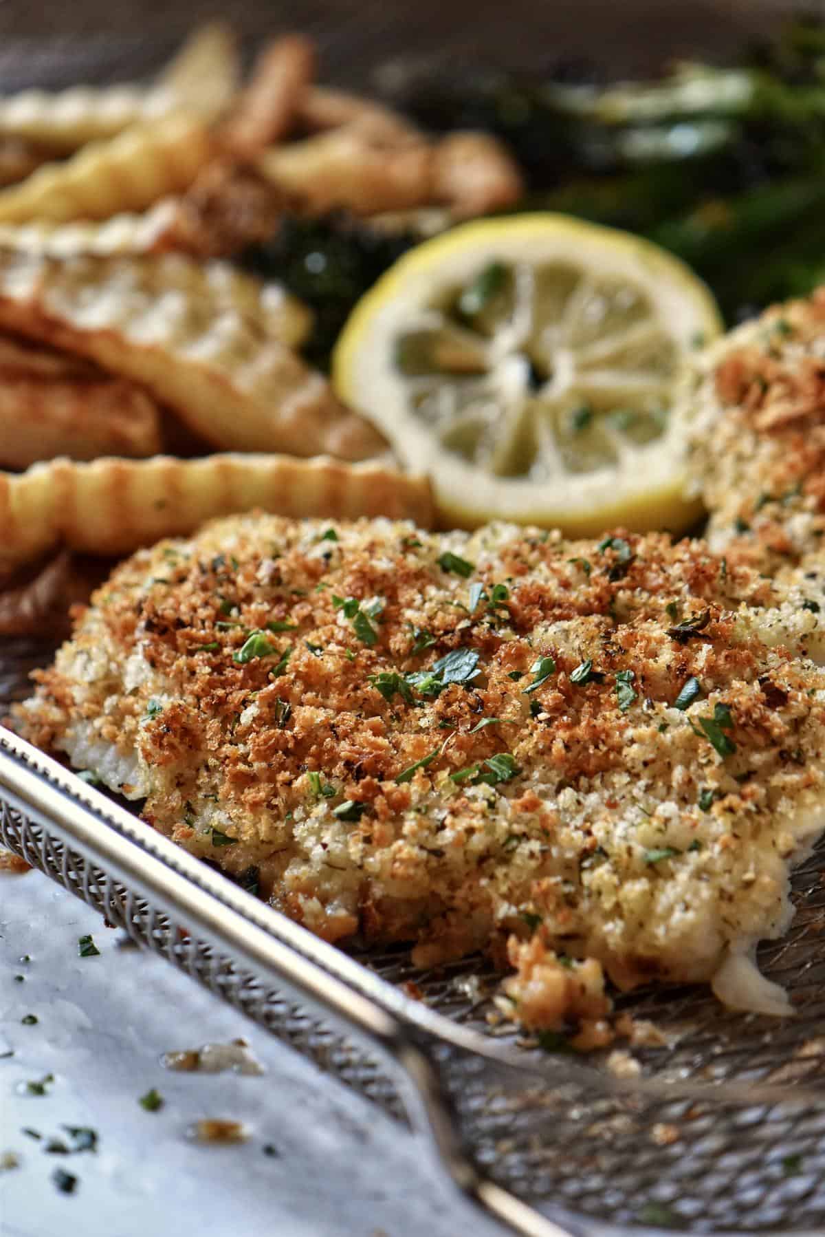 Air fried cod with crinkle potatoes on an air fryer basket. 