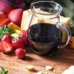 Balsamic glaze in a jar, next to fresh strawberries.