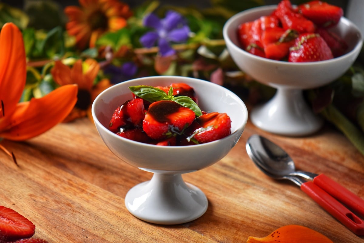 Balsamic glazed strawberries in a white dessert bowl.