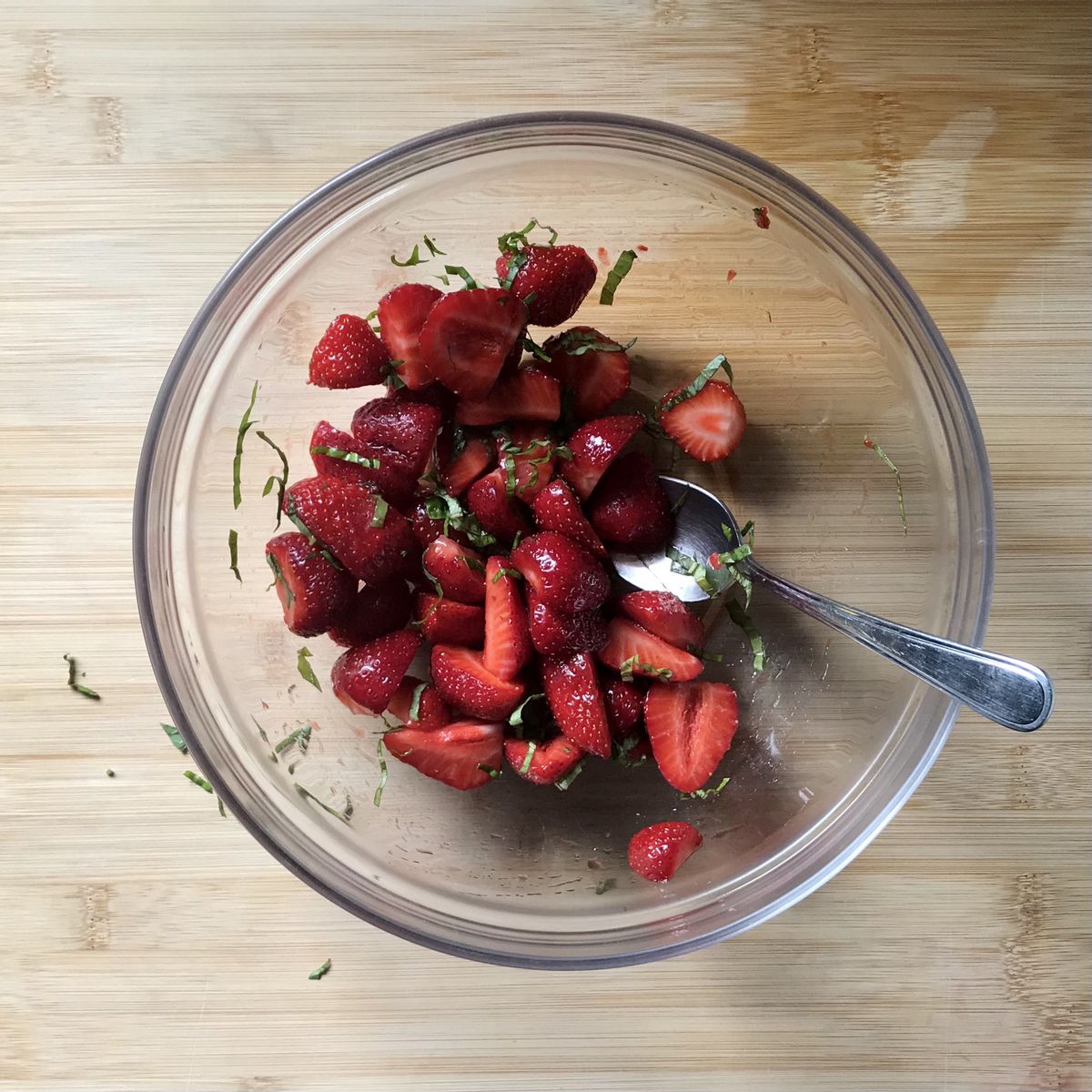 Basil and strawberries combined in a large bowl. 