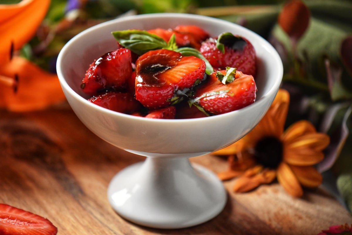 Balsamic glazed strawberries in a white dessert bowl.