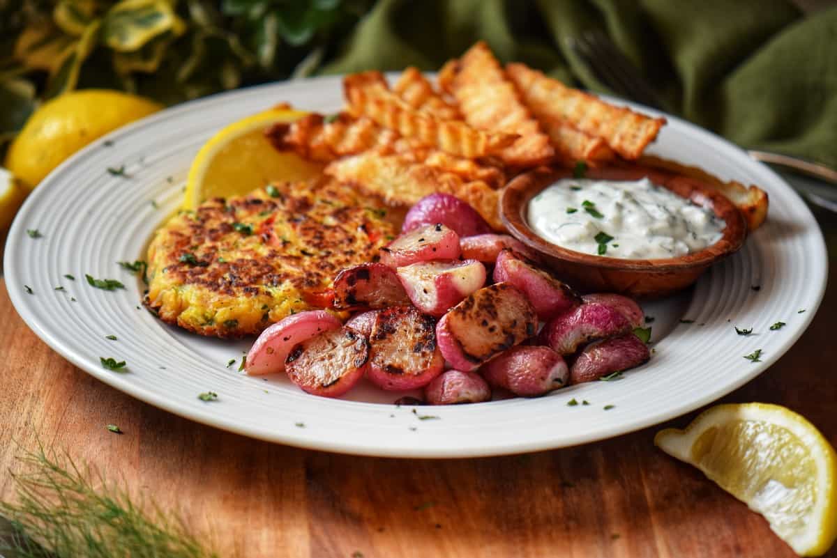 Roasted radishes next to tuna patties on a white plate.