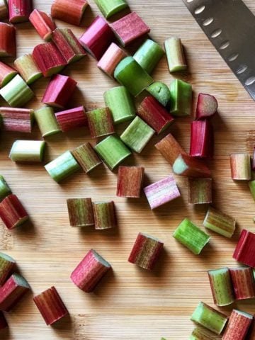 Fresh rhubarb cut into pieces on a wooden board.