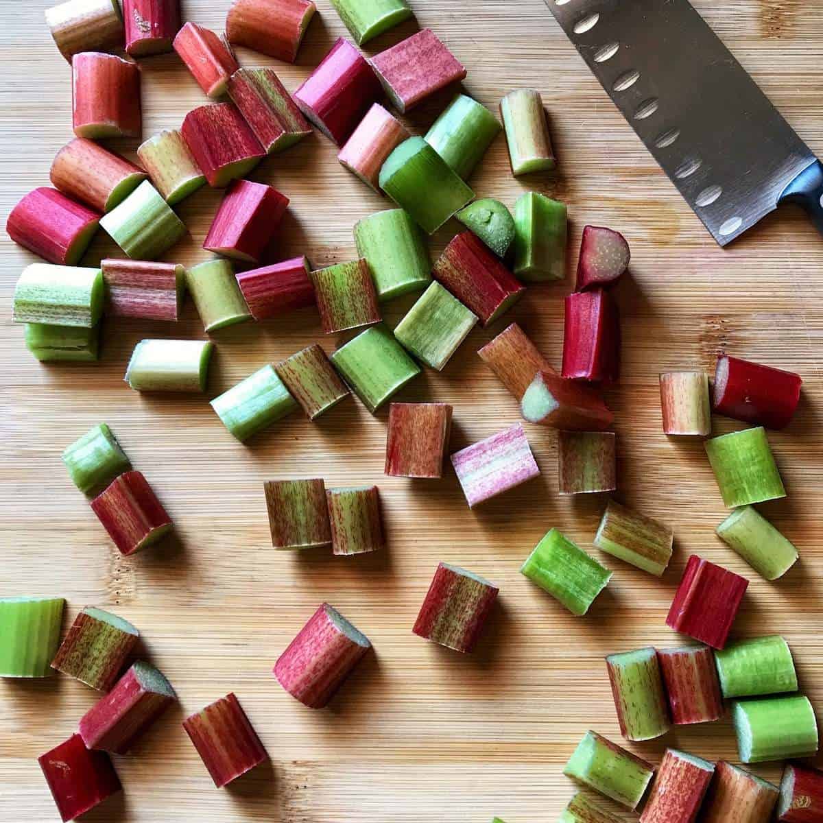 Fresh rhubarb cut into pieces on a wooden board.