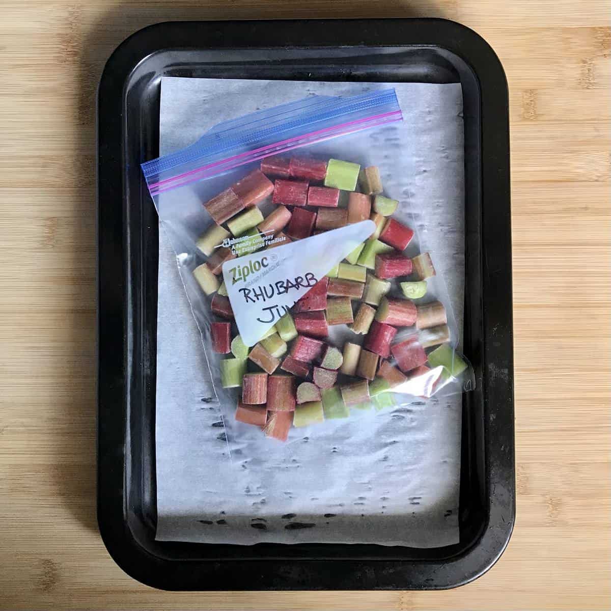 Frozen rhubarb in a Ziploc bag on a baking tray.