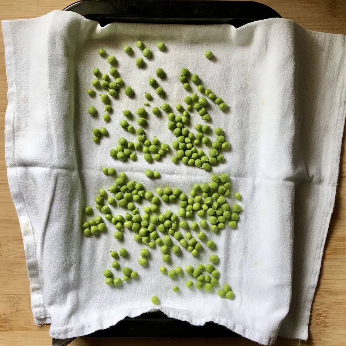 Freshly blanched peas drying off on a tea towel. 