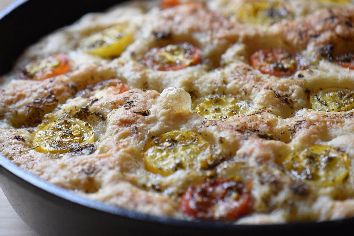 Tomato focaccia with herbs in a cast iron skillet.