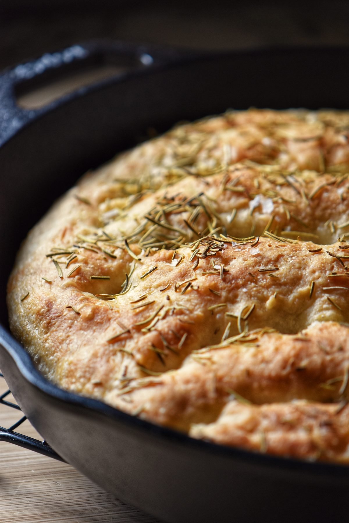 Cast iron focaccia dough garnished with rosemary. 