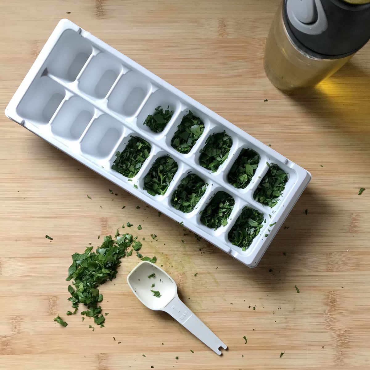 Chopped parsley in the cavities of an ice cube ready ready to be frozen.