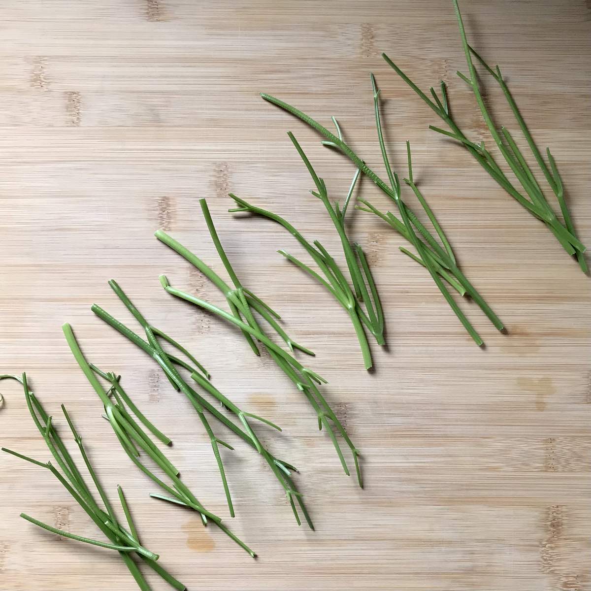Small bundles of parsley stalks on a wooden board.