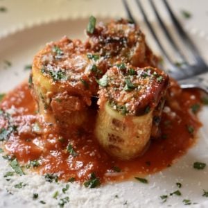 Zucchini lasagna rolls on a white plate.