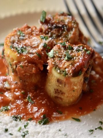 Zucchini lasagna rolls on a white plate.