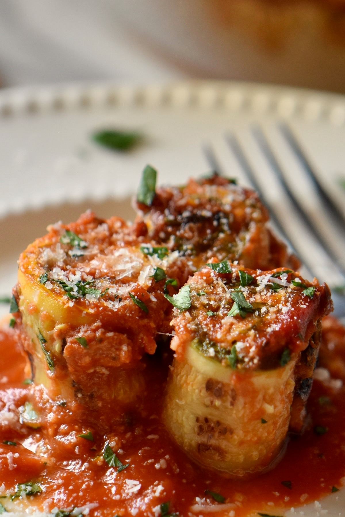 Zucchini lasagna rolls on a white plate.