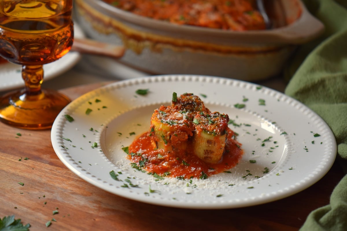 Zucchini rolls with ricotta on a white plate.