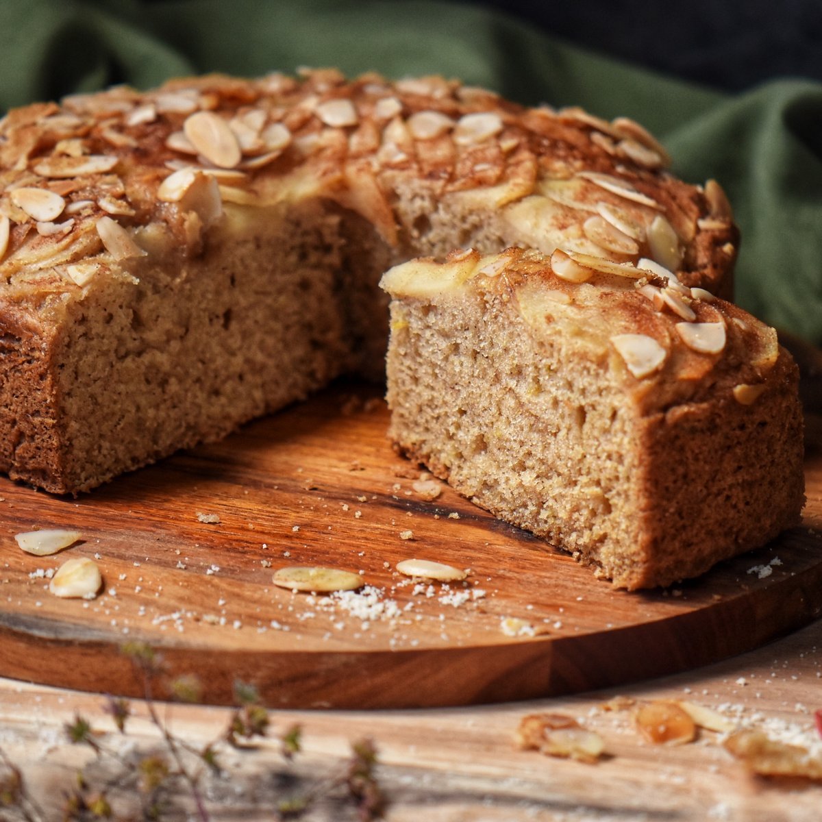 A slice of pear cake on a wooden board.