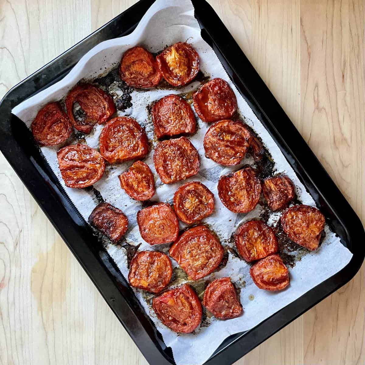 Oven roasted Roma tomatoes on a parchment lined pan.