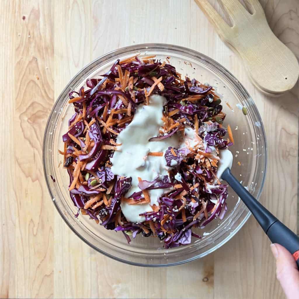 A creamy salad dressing over a carrot and cabbage slaw.