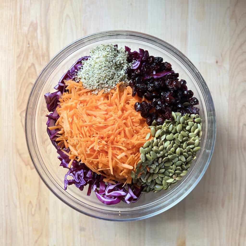 Slaw ingredients such as shredded carrots and cabbage in a large bowl.