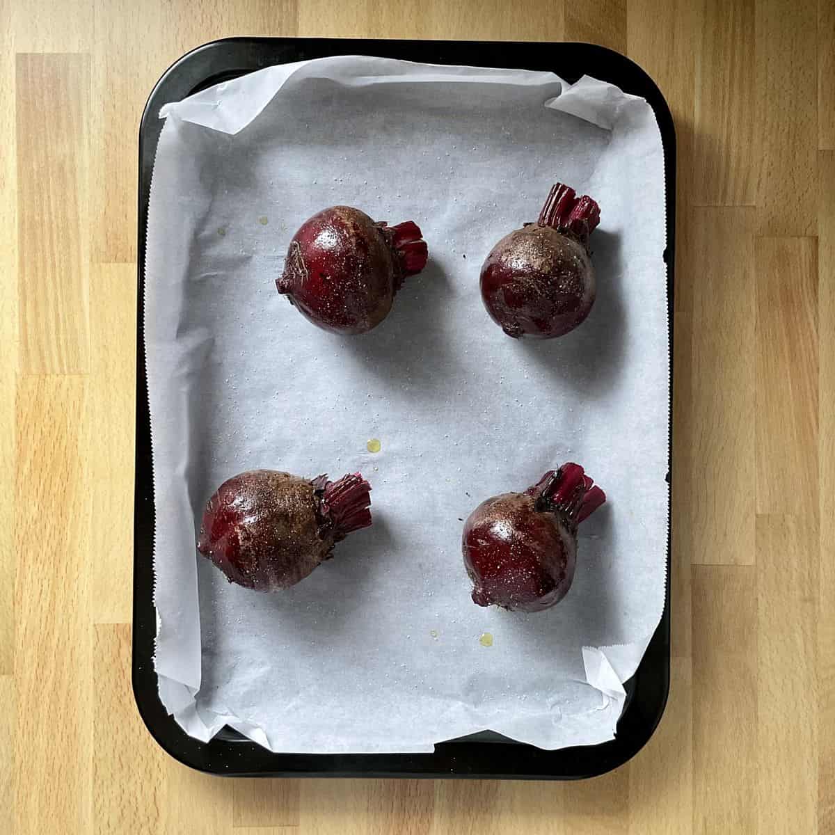 Fresh beets on paper-lined baking sheet.