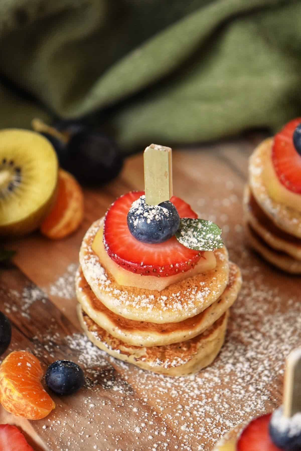 A stack of three mini pancakes with fruit.