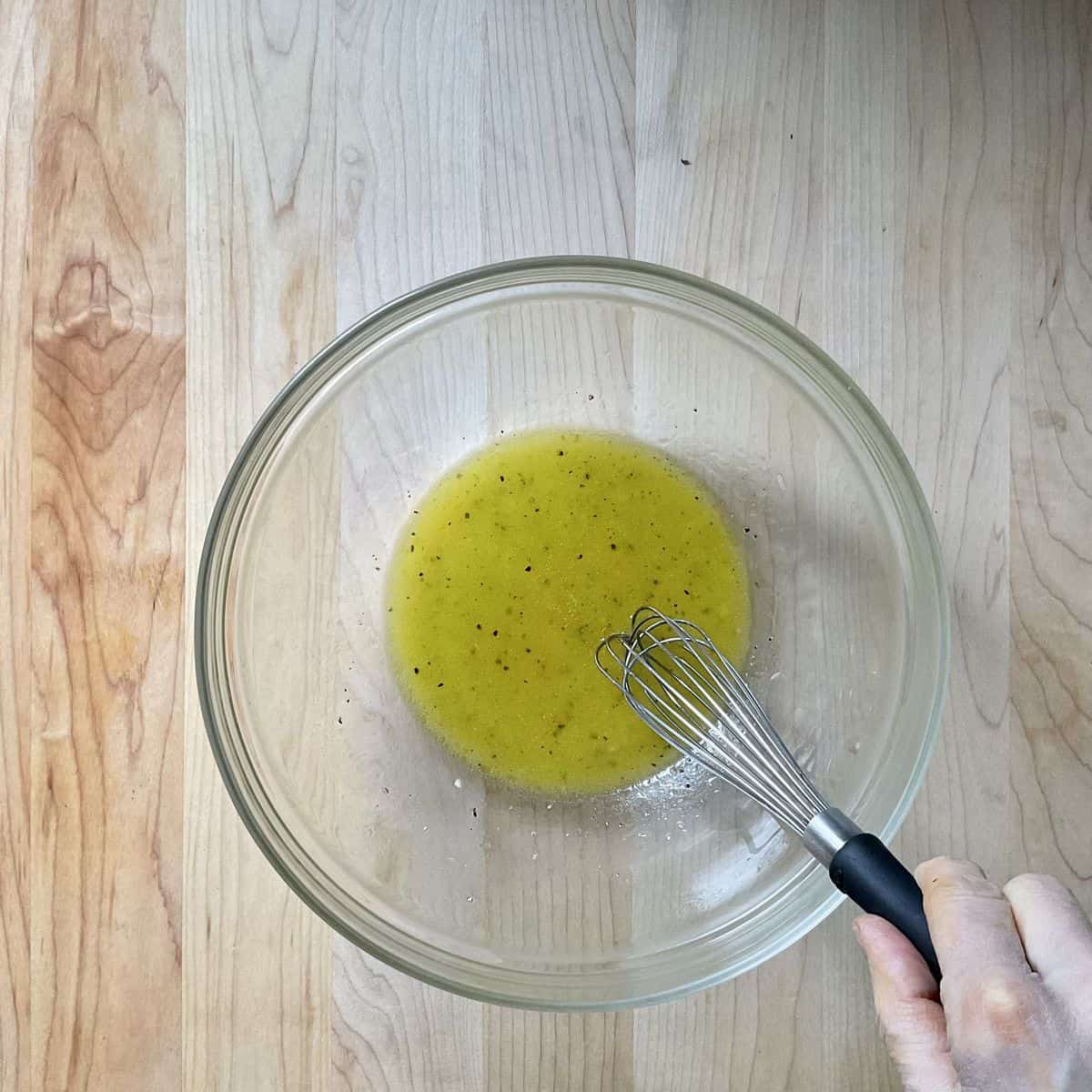 The salad dressing being whisked together in a bowl.