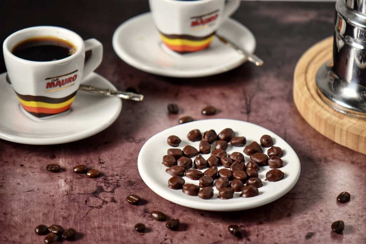 Chocolate coffee beans on a white dish.