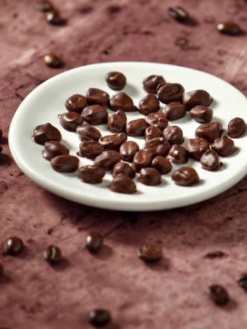 chocolate covered espresso beans on a white dish.