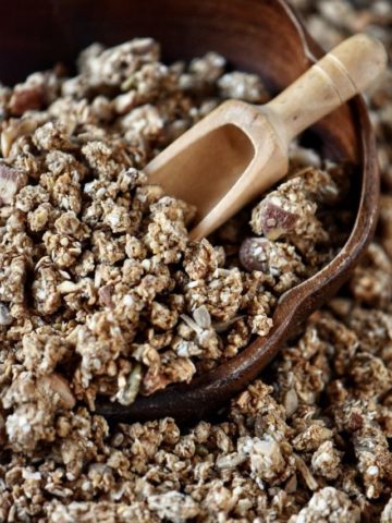 A wooden bowl of clusters of granola.