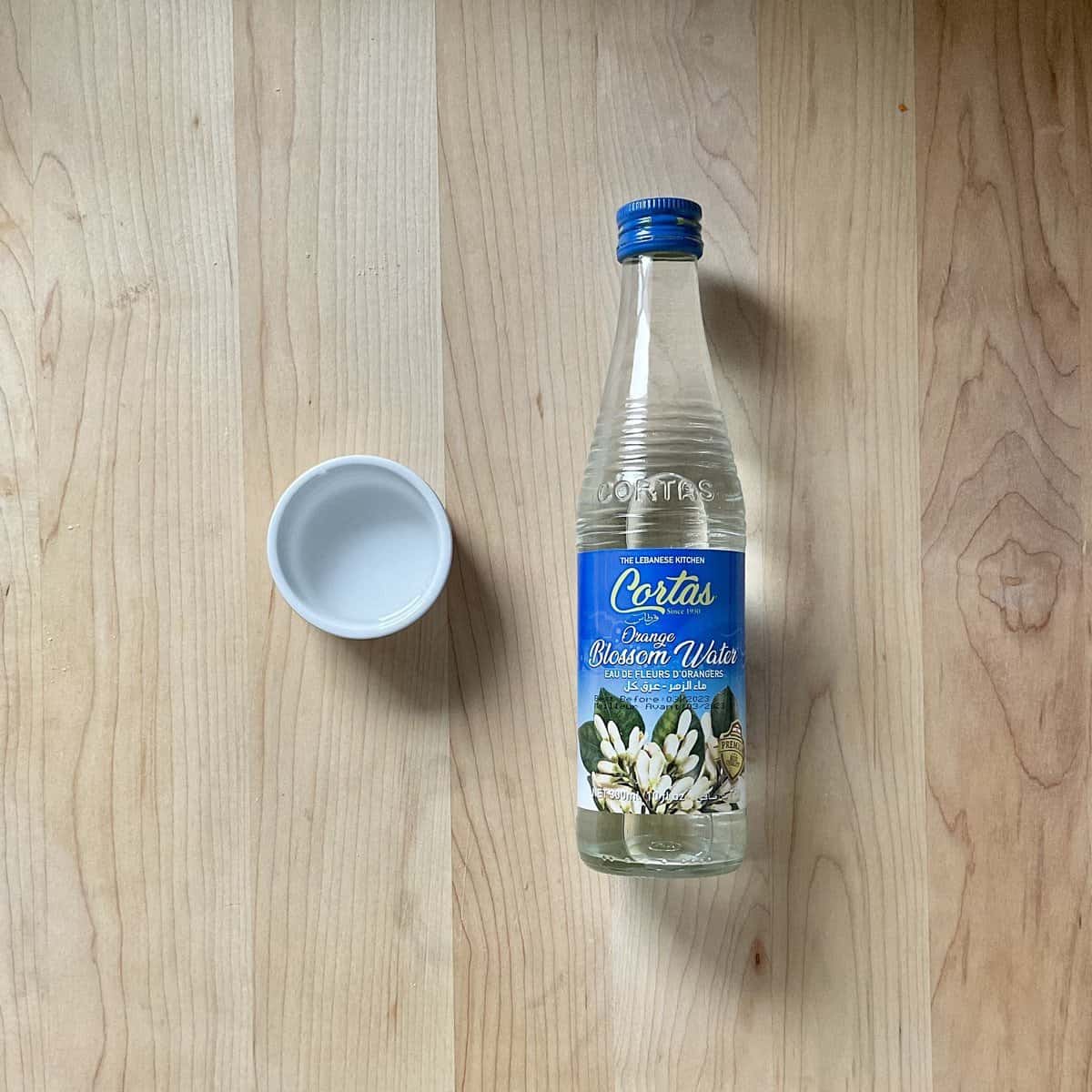 A bottle of orange blossom water on a wooden surface.