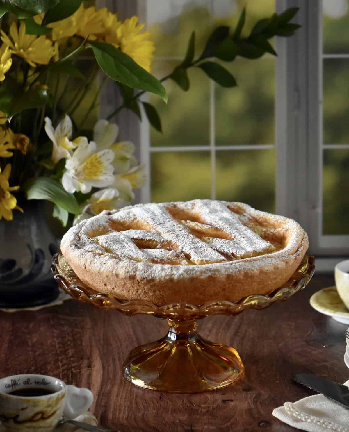 Pasteria Napoletana on an amber colored cake stand set before a window,
