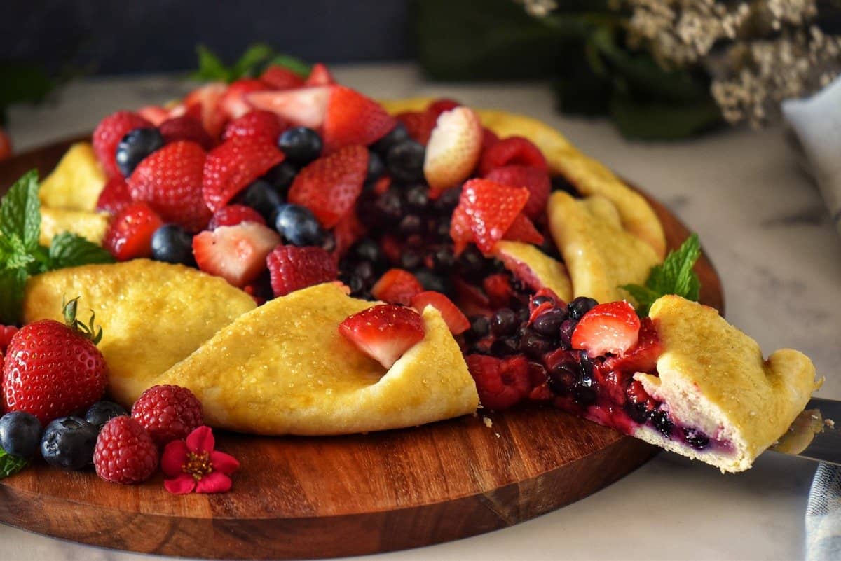 A slice of fruit crostata being removed form the dessert.