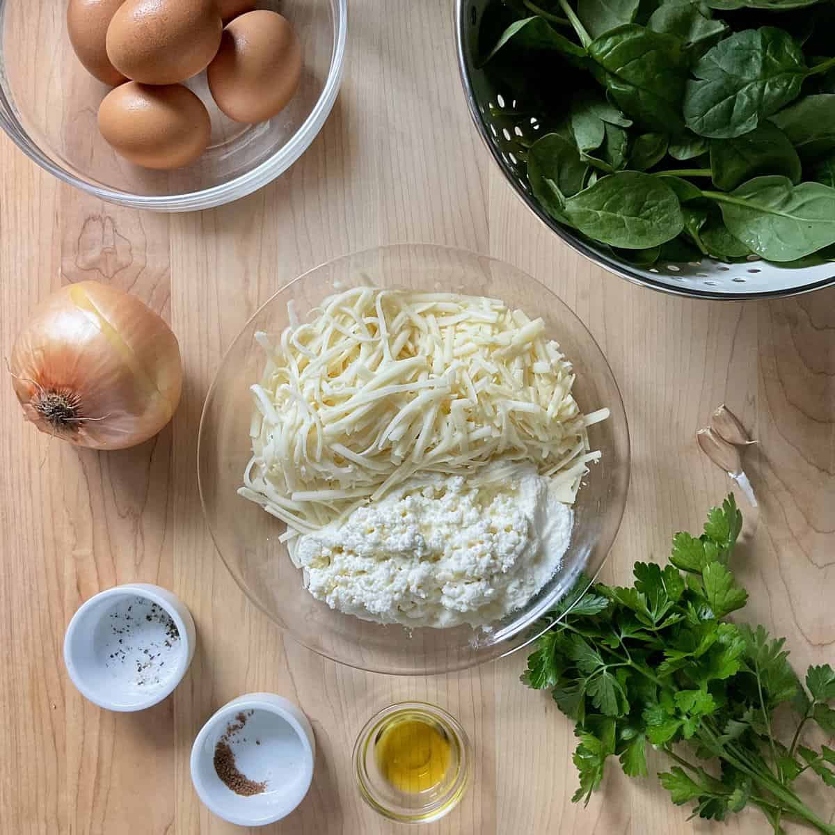 Ingredients to make a spinach quiche without a crust on a wooden board.