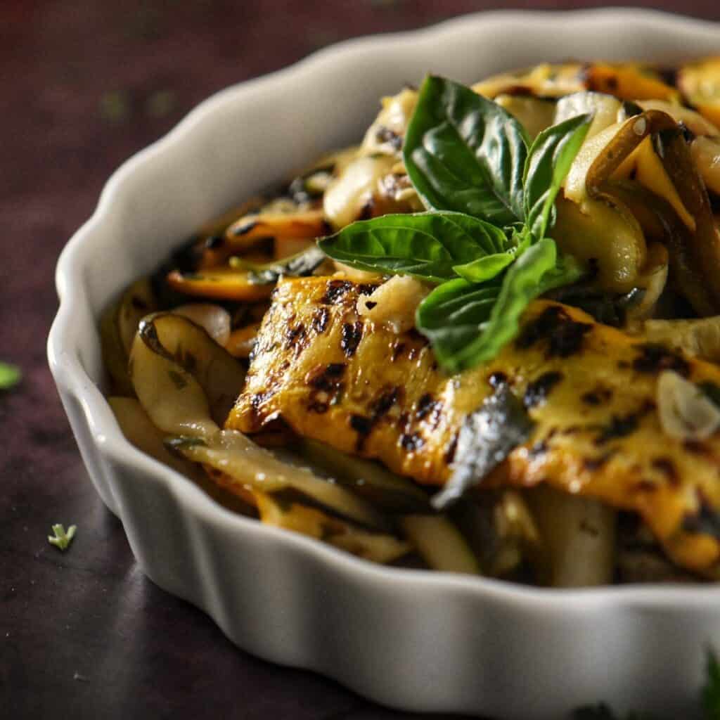 Yellow and green grilled zucchini in a white dish.