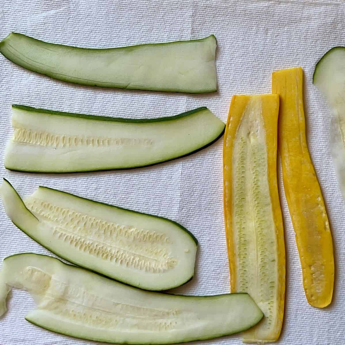 Sliced zucchini drying off on a paper towel.