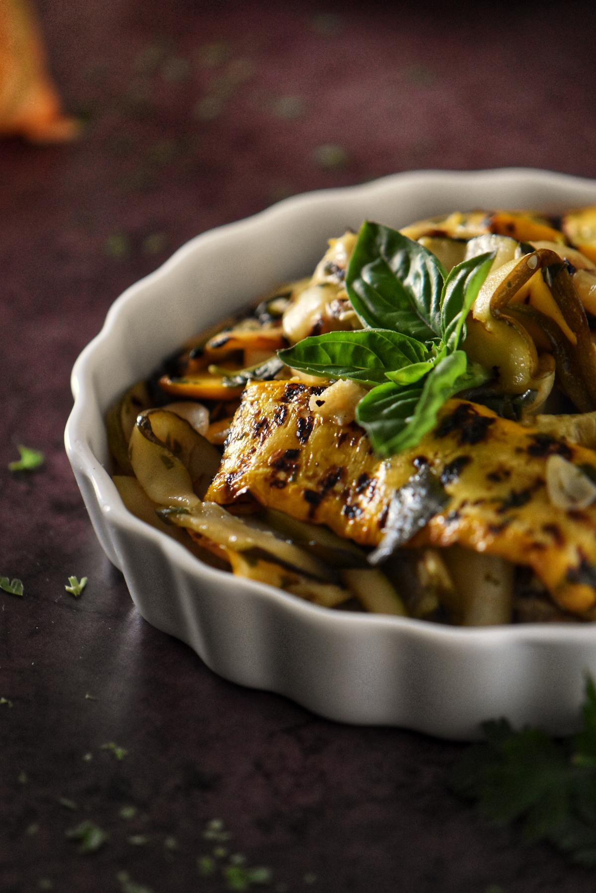 Grilled zucchini with basil in a white dish.