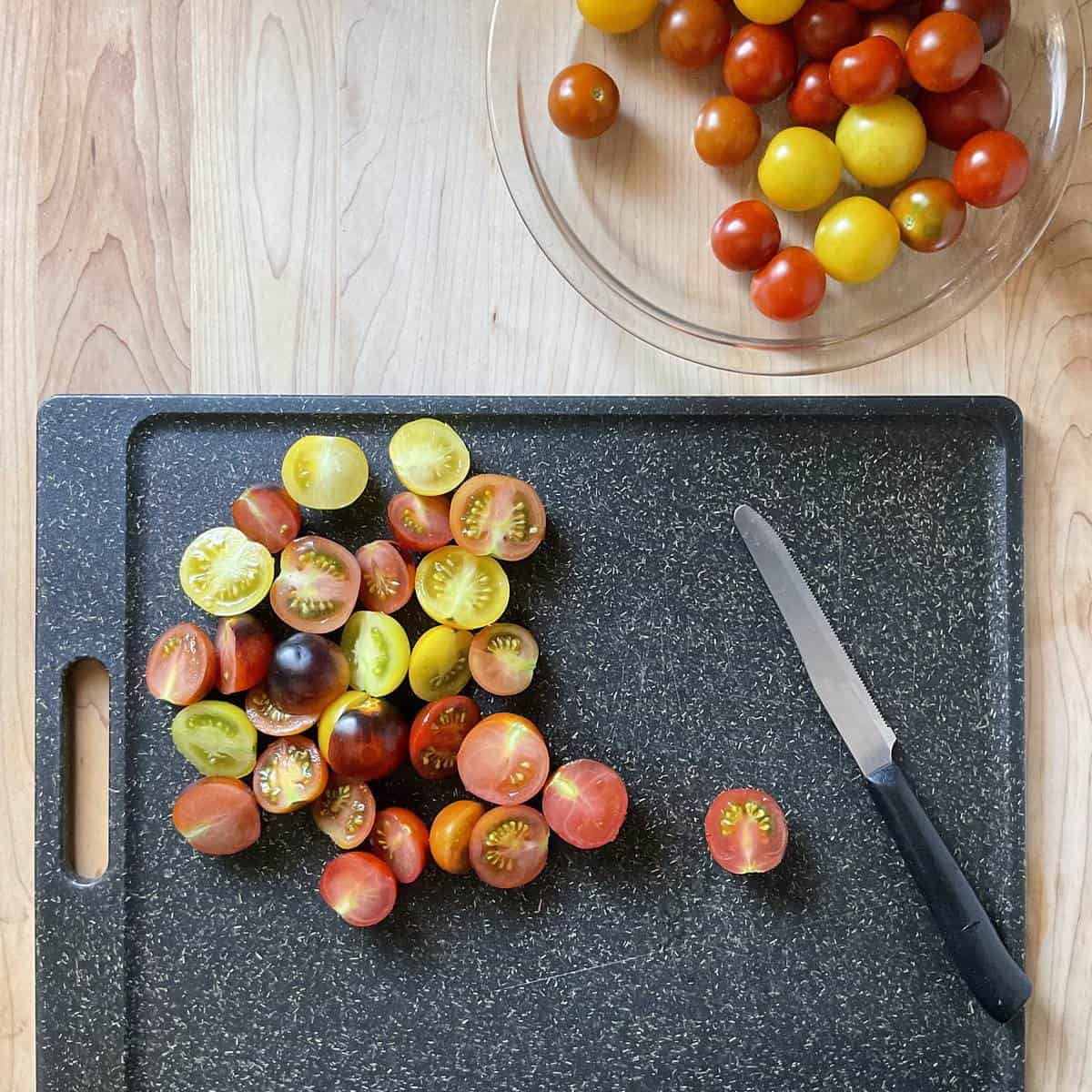 Sliced cherry tomatoes on a cutting board.